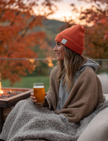 Woman sitting outside enjoying a beer by the fire