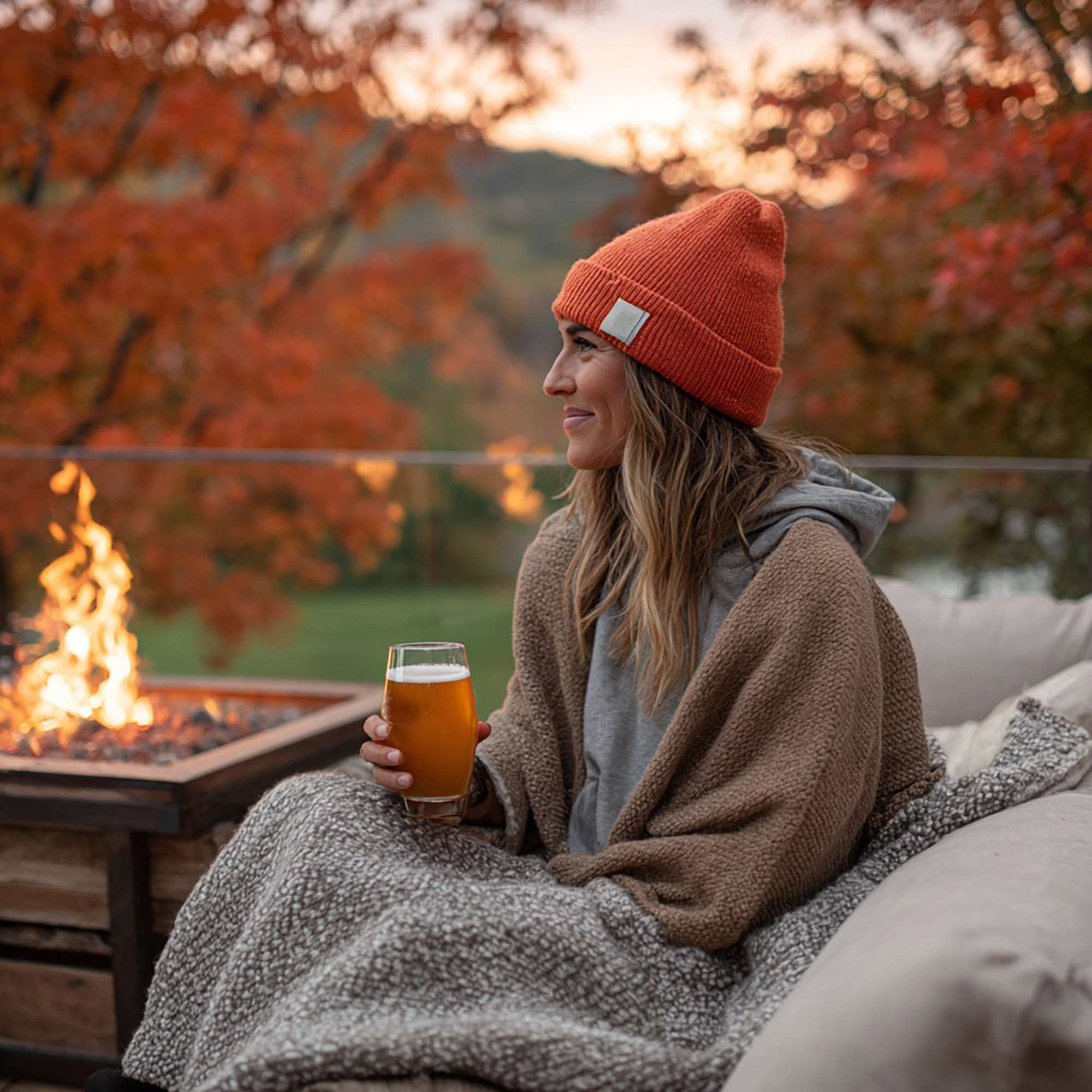 Woman sitting outside enjoying a beer by the fire